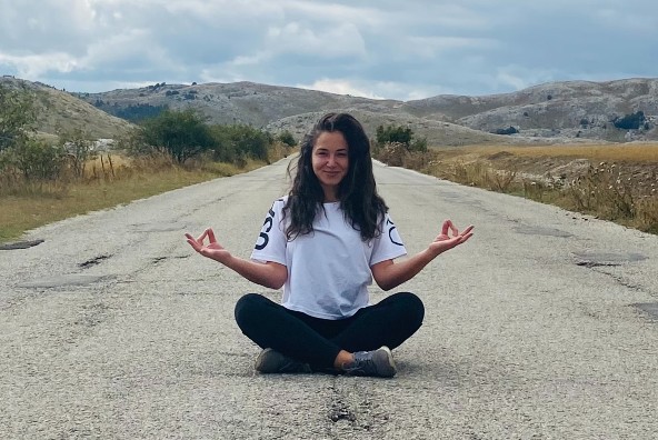 A woman sitting on a road in a yoga pose