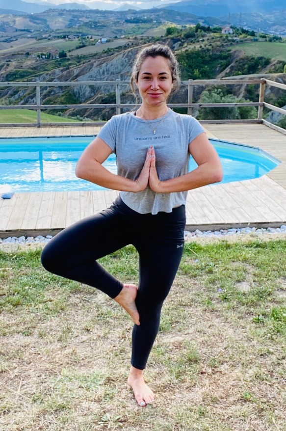 A woman in a yoga pose next to a swimming pool