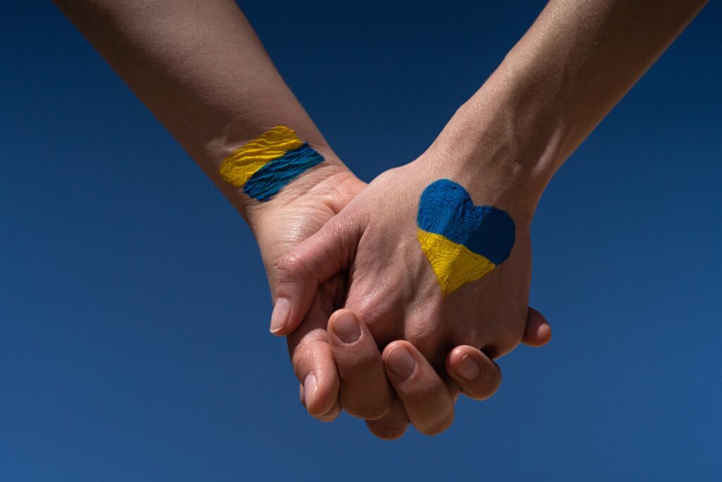 Two hands holding the other, with the Ukrainian colours on them