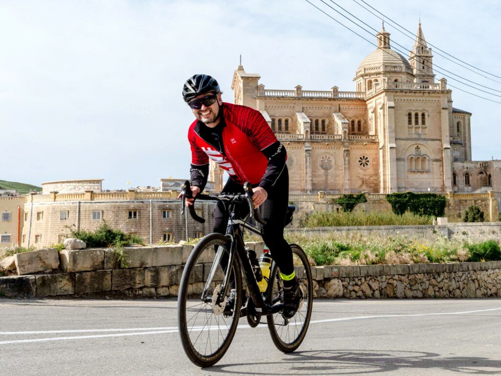 A man on a bicycle with a church in the background